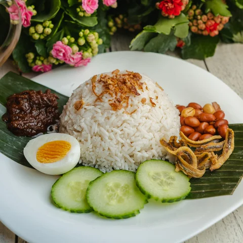 Nasi lemak served with sambal, anchovies, peanuts, boiled egg and cucumber